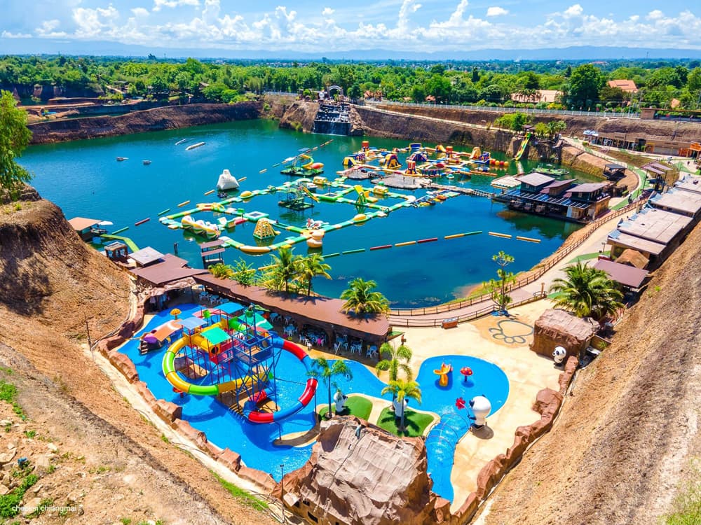 Aerial view of the turquoise quarry lake at Grand Canyon Water Park, ringed by ochre cliffs and jungle