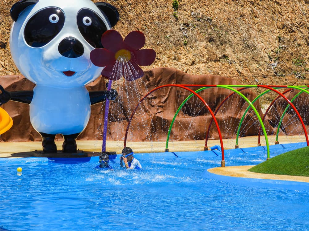 A child plays under the panda fountain in the shallow kids zone